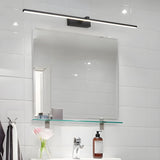 Bar lit above a square mirror in a white tiled bathroom with a glass shelf