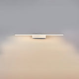 The short white bar lit on a gray wall, the glow pooling under the fitting