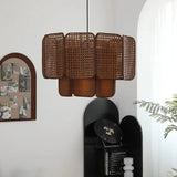 Brown wicker hanging lamp lit in an interior with a plant