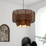 Wicker hanging lamp with a two tier scalloped shade in brown, lit in a room