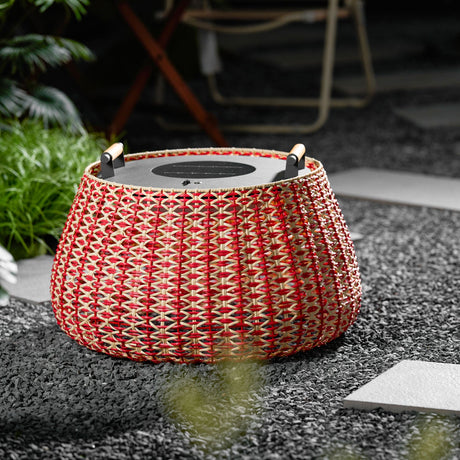 The lantern lit at the edge of a gravel path with grasses around it