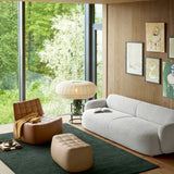 Broad knitted cloth shade lit above a sofa in front of a garden window