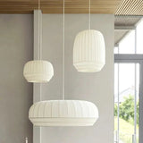 Wide ceiling light in hand knitted cloth, three shades beside a window