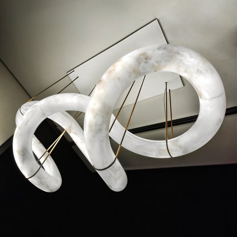A long winding alabaster ribbon lit, held on brass cables from a slim frame