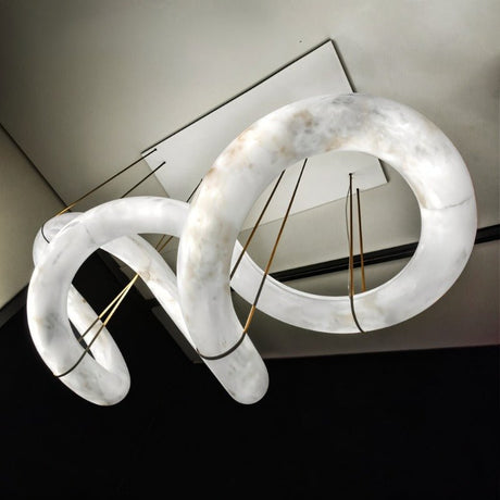A long winding alabaster ribbon lit, held on brass cables from a slim frame