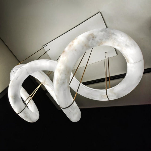 A long winding alabaster ribbon lit, held on brass cables from a slim frame