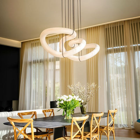 The lit ribbon above a dining table with chairs, flowers and long curtains