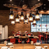 Hung over red chairs and wood tables in a room with a brick wall and windows