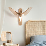 Sconce lit beside a cane headboard above a bedside table with a frame