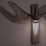The pierced wings throwing a patterned shadow across a dark wall