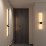 Lit either side of a dark entry door above a stone floor and a low console
