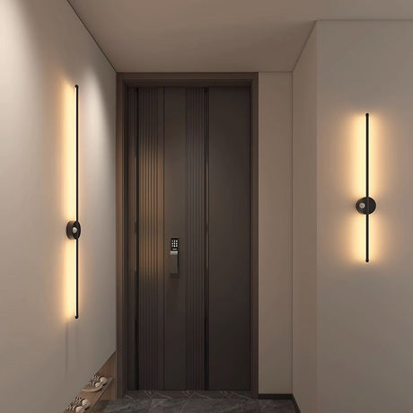 Lit either side of a dark entry door above a stone floor and a low console