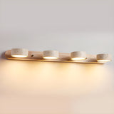 Four travertine discs lit along a long light wood bar