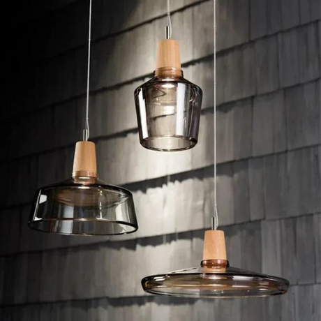 Two smoked glass and wood pendants lit against a dark tiled wall