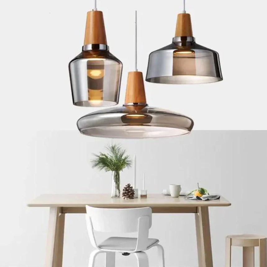 Three pendants of different shapes lit above a wooden dining table