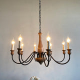 The chandelier lit against a soft gray wall, arms looping under the candle sleeves