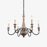 Six black arms looping out of a pale turned wood column with candle sleeves on top