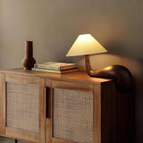 Wood desk lamp lit on a cane fronted cabinet beside a vase