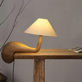 Wood desk lamp lit at the edge of a wooden console against a wall