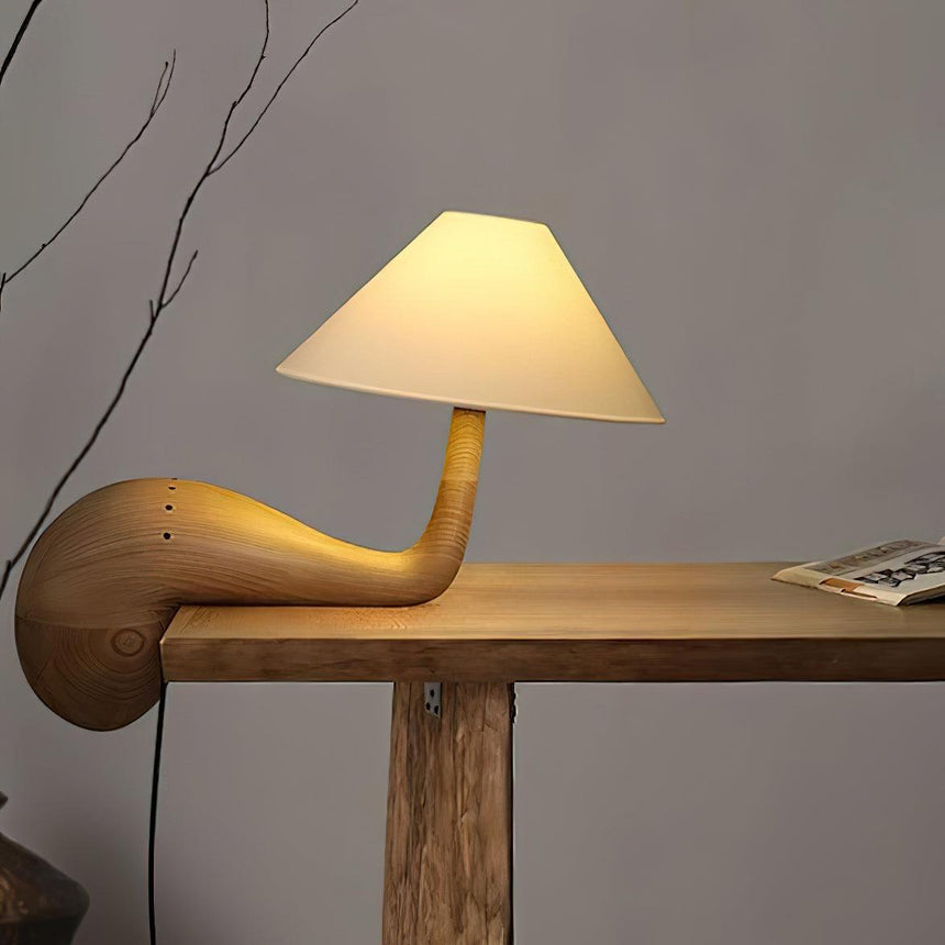 Wood desk lamp lit at the edge of a wooden console against a wall