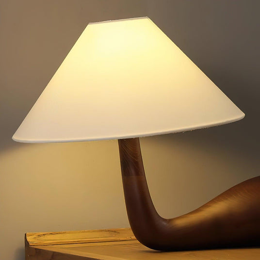 Close view of the lit white cone shade above the carved wood arm