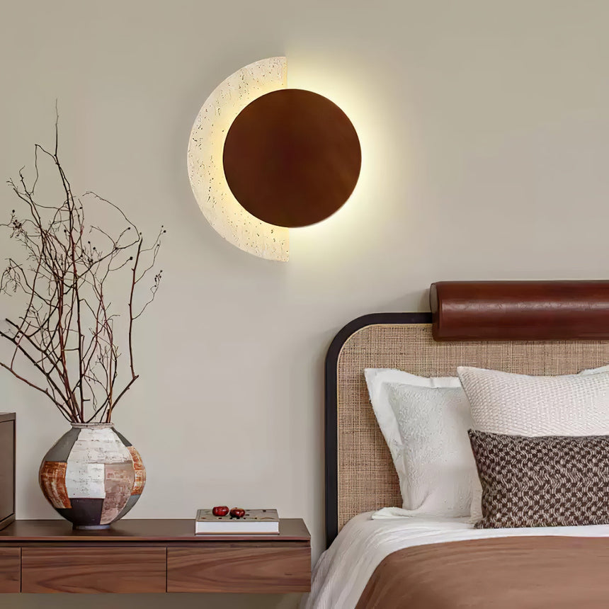 Plug in sconce lit on a bedroom wall above a vase of dried branches