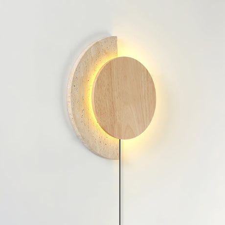Light wood disc lit over a travertine crescent, the halo glowing behind