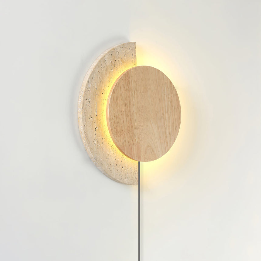 Light wood disc lit over a travertine crescent, the halo glowing behind