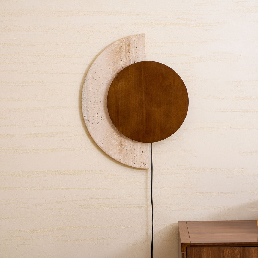 Plug in sconce lit on a pale wall above a wood cabinet, cord running down