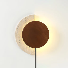 Walnut disc lit over a travertine crescent, warm halo around the edge