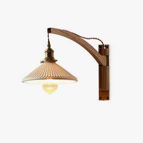 Walnut wall light with a curved wood arm and a pleated white ceramic shade on a brass socket