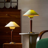 Green and tan wood table lamps lit side by side on a sideboard