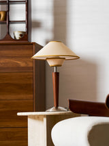 Tan shade wood table lamp lit on a dark wooden console