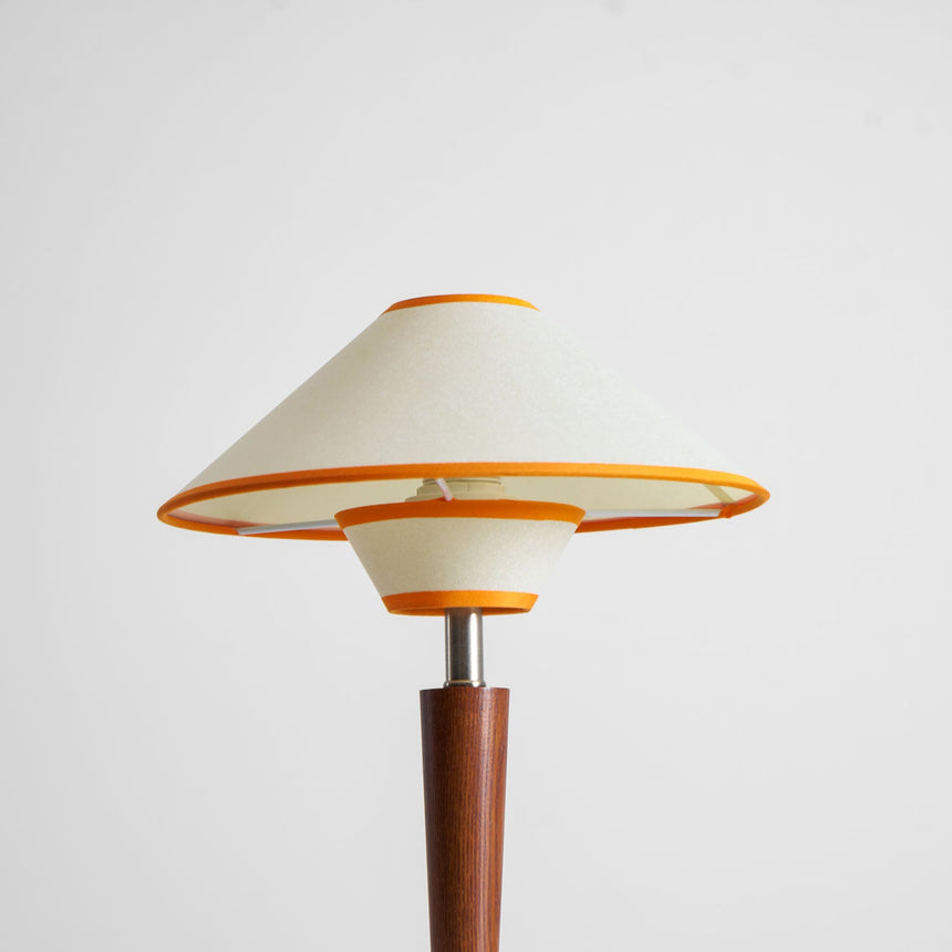 Wood table lamp with the tan two tier shade on a plain background