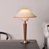 Wood table lamp with a two tier fabric shade lit beside an armchair