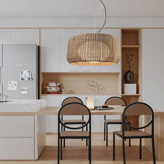 The lit shade above a pale kitchen table with two black chairs and open shelving