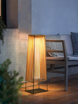 The lamp lit on a balcony beside an outdoor sofa with patterned pillows