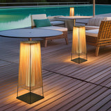 Two lit on poolside decking beside round tables and woven seating