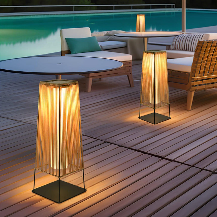 Two lit on poolside decking beside round tables and woven seating