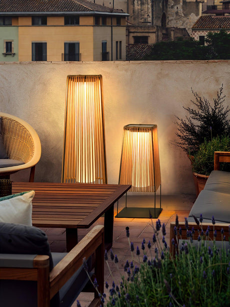 Two lit on a terrace beside a timber table and a woven armchair