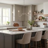 Lit above a white kitchen island with upholstered stools and cabinets behind
